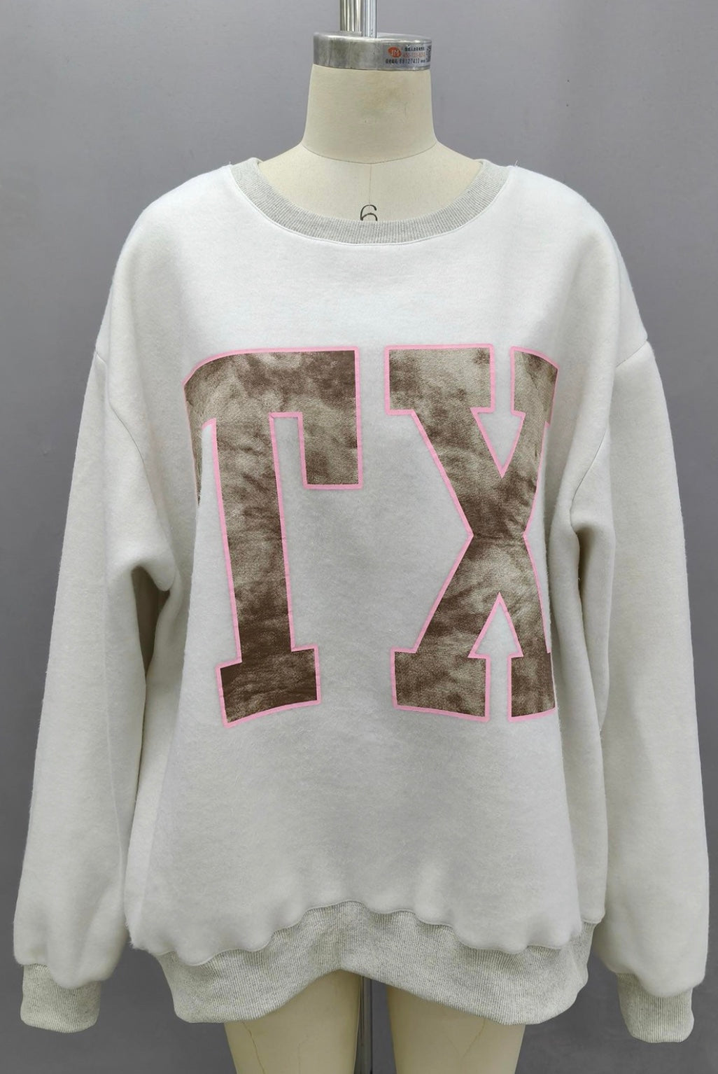 White sweatshirt with pink and brown design on a mannequin against a gray background