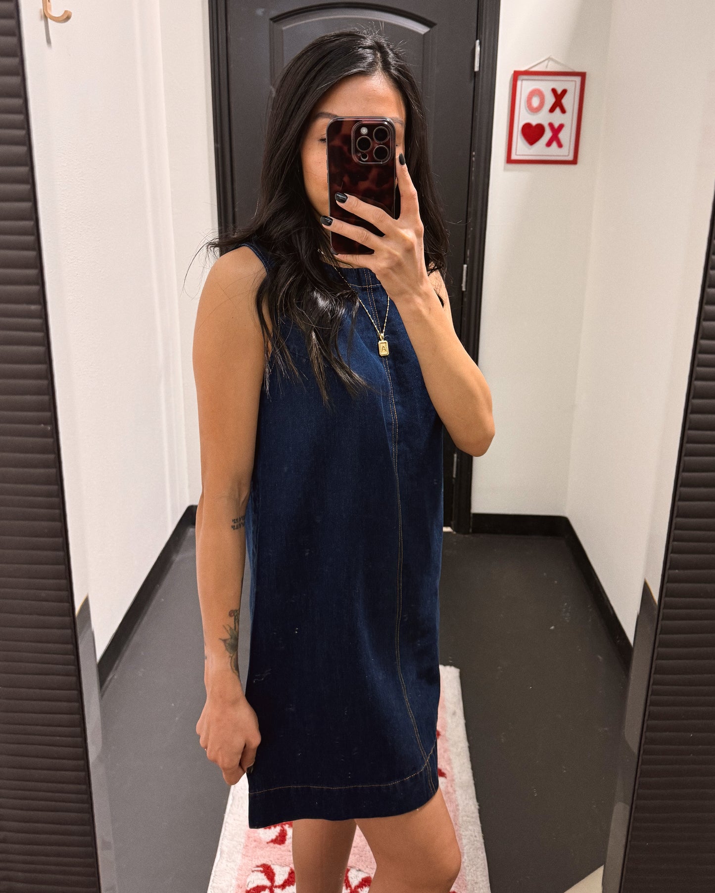 Person wearing a blue dress taking a mirror selfie in a fitting room.
