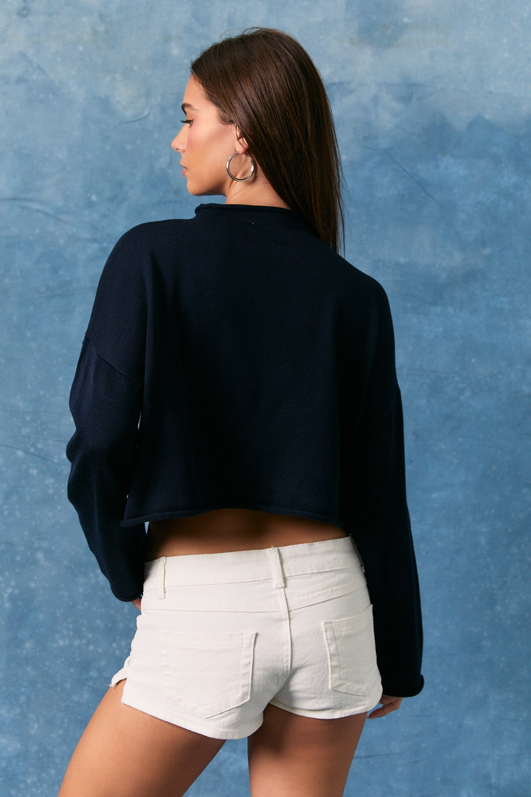 Woman wearing a navy cropped mock neck sweater with white USA lettering and long sleeves. 🤍🇺🇸