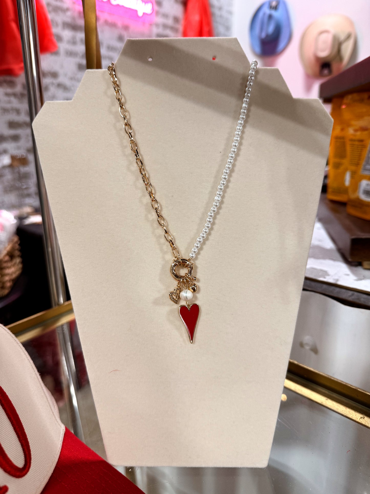 Necklace with a red heart pendant on a white stand in a store setting