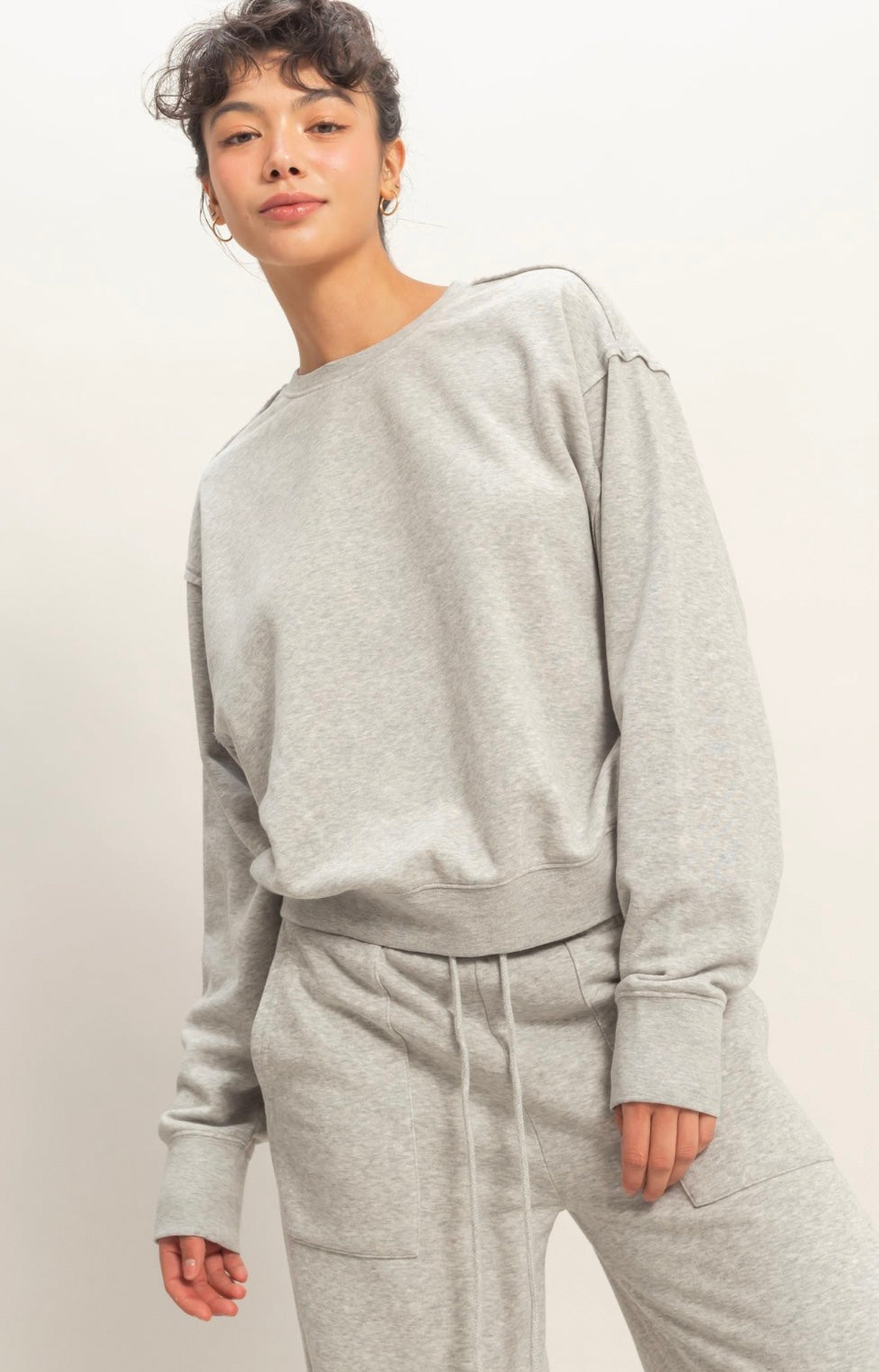 Person wearing a gray sweatshirt and pants against a plain background