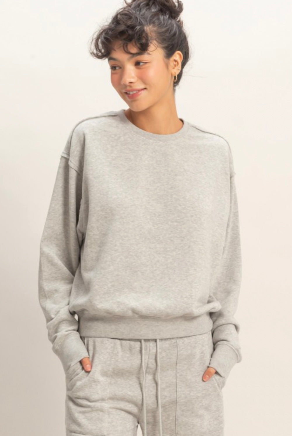 Person wearing a gray sweatshirt and pants on a light background