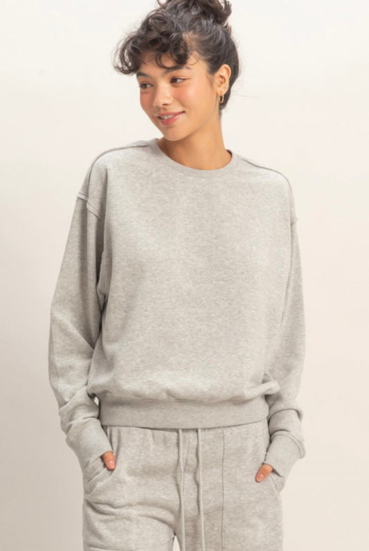 Person wearing a gray sweatshirt and pants on a light background