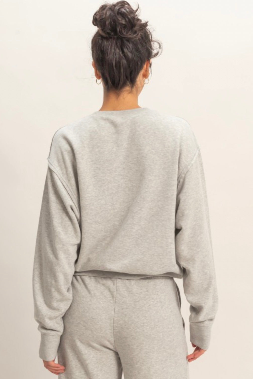 Person wearing a gray sweatshirt and pants set against a plain background