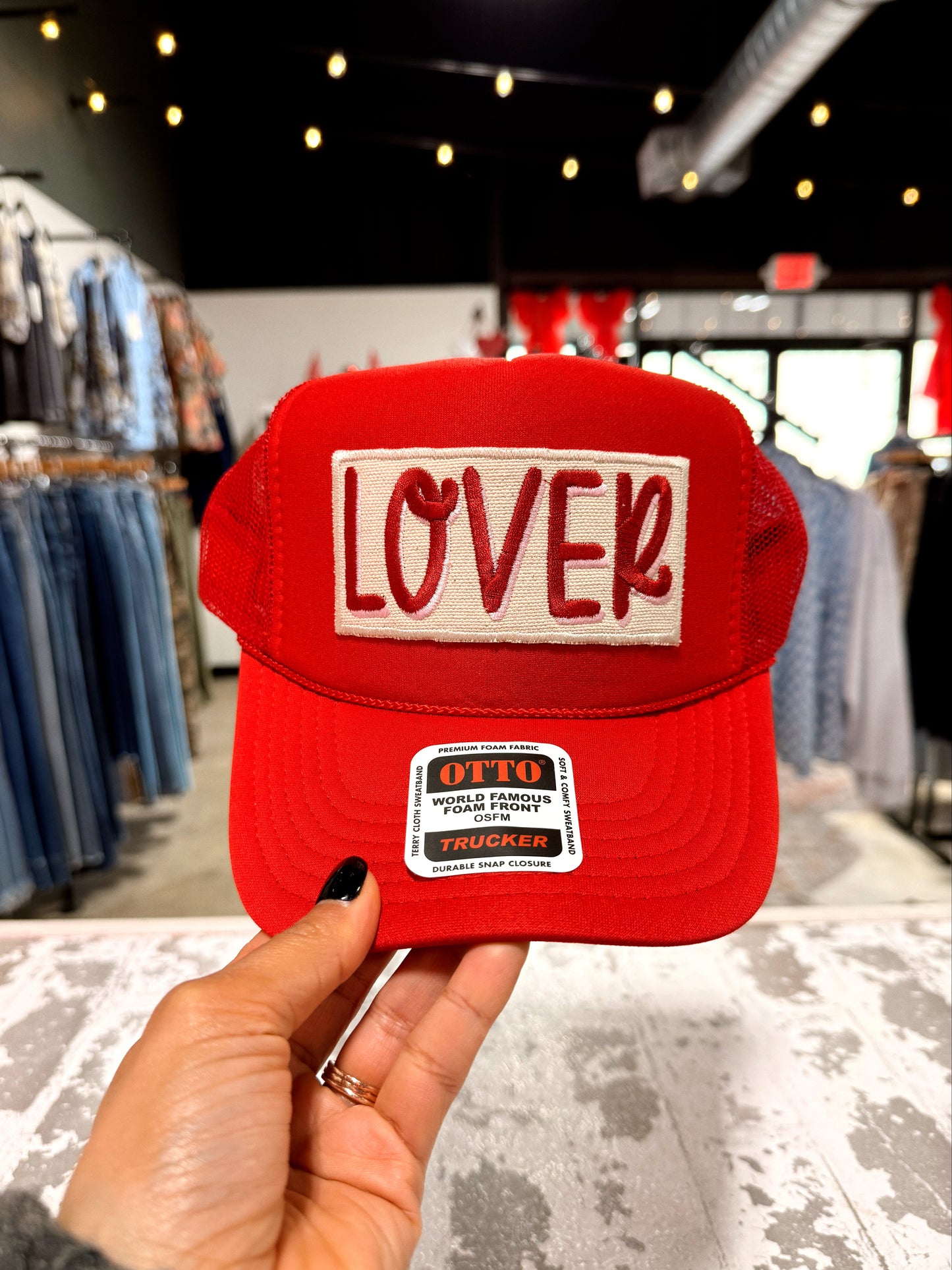 Red cap with 'LOVER' text held in a store setting