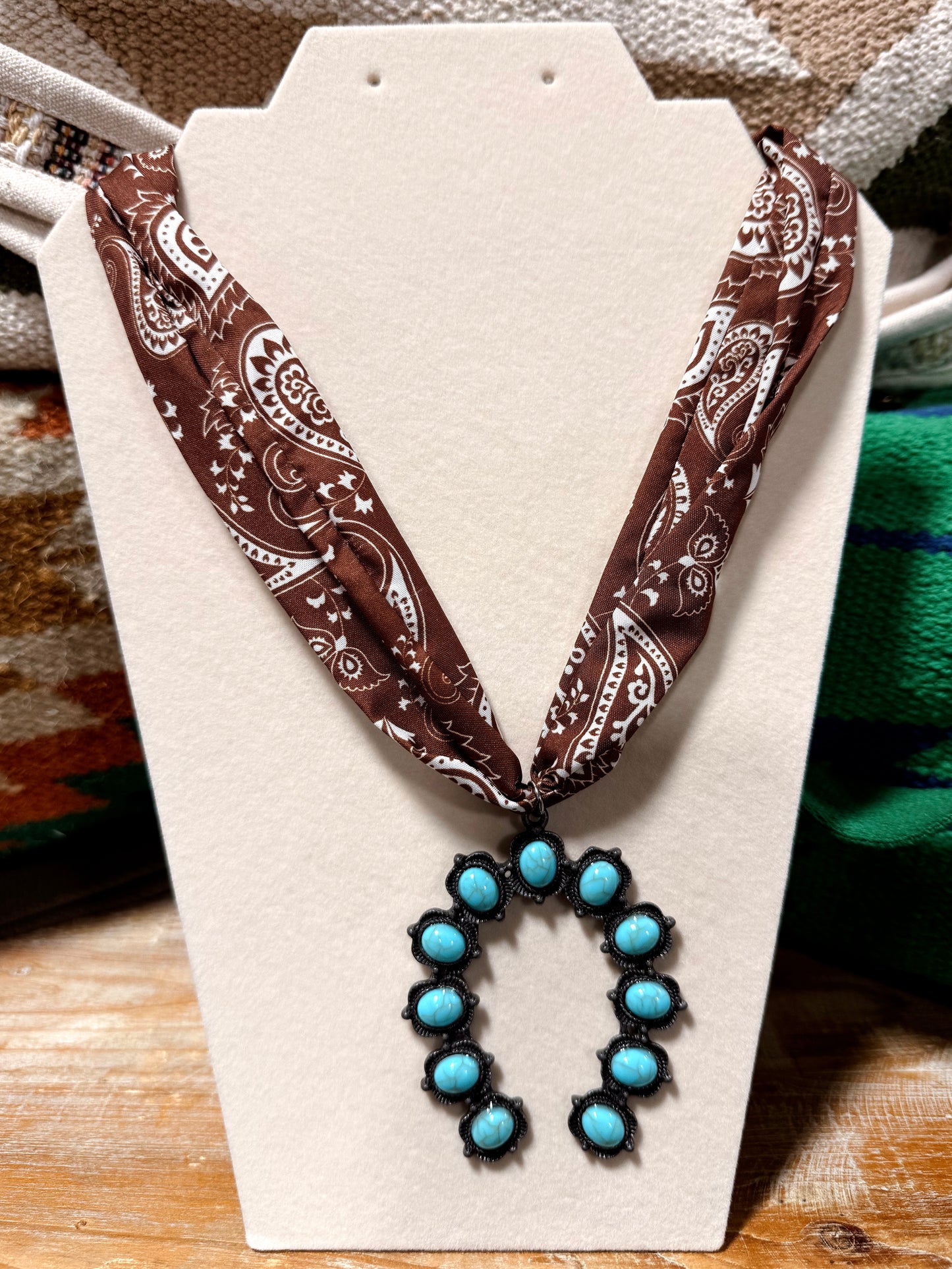 Necklace with brown bandana-style strap and turquoise pendant on a white card.