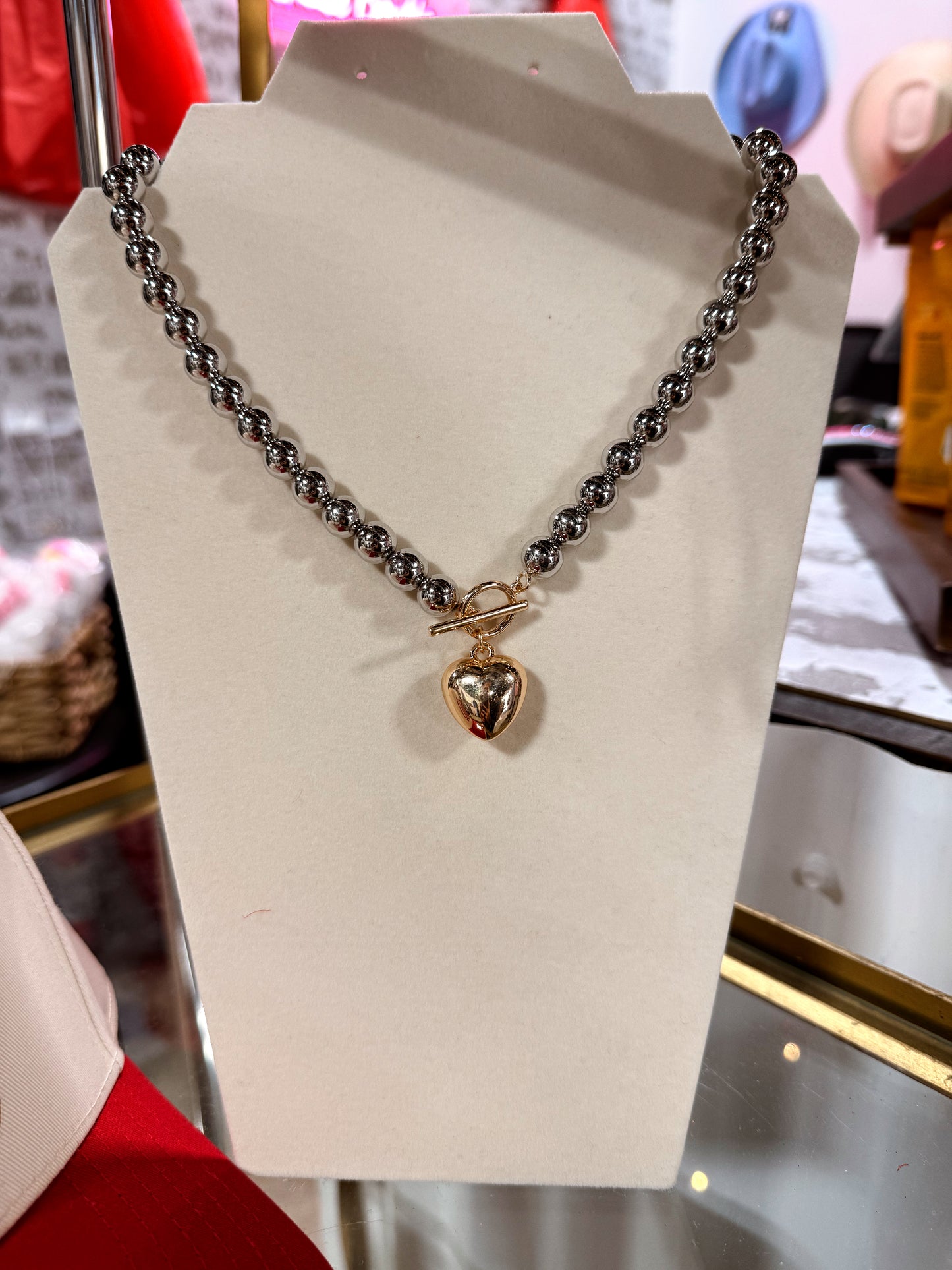 Necklace with a heart-shaped pendant on a beige stand