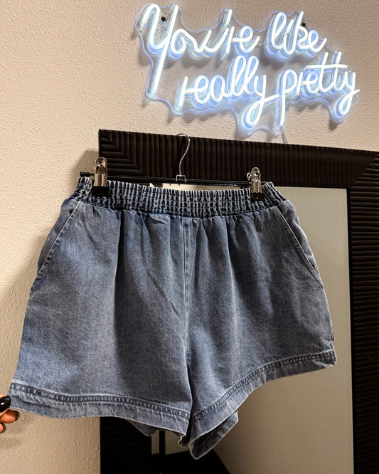 Denim shorts on a hanger with a neon sign above